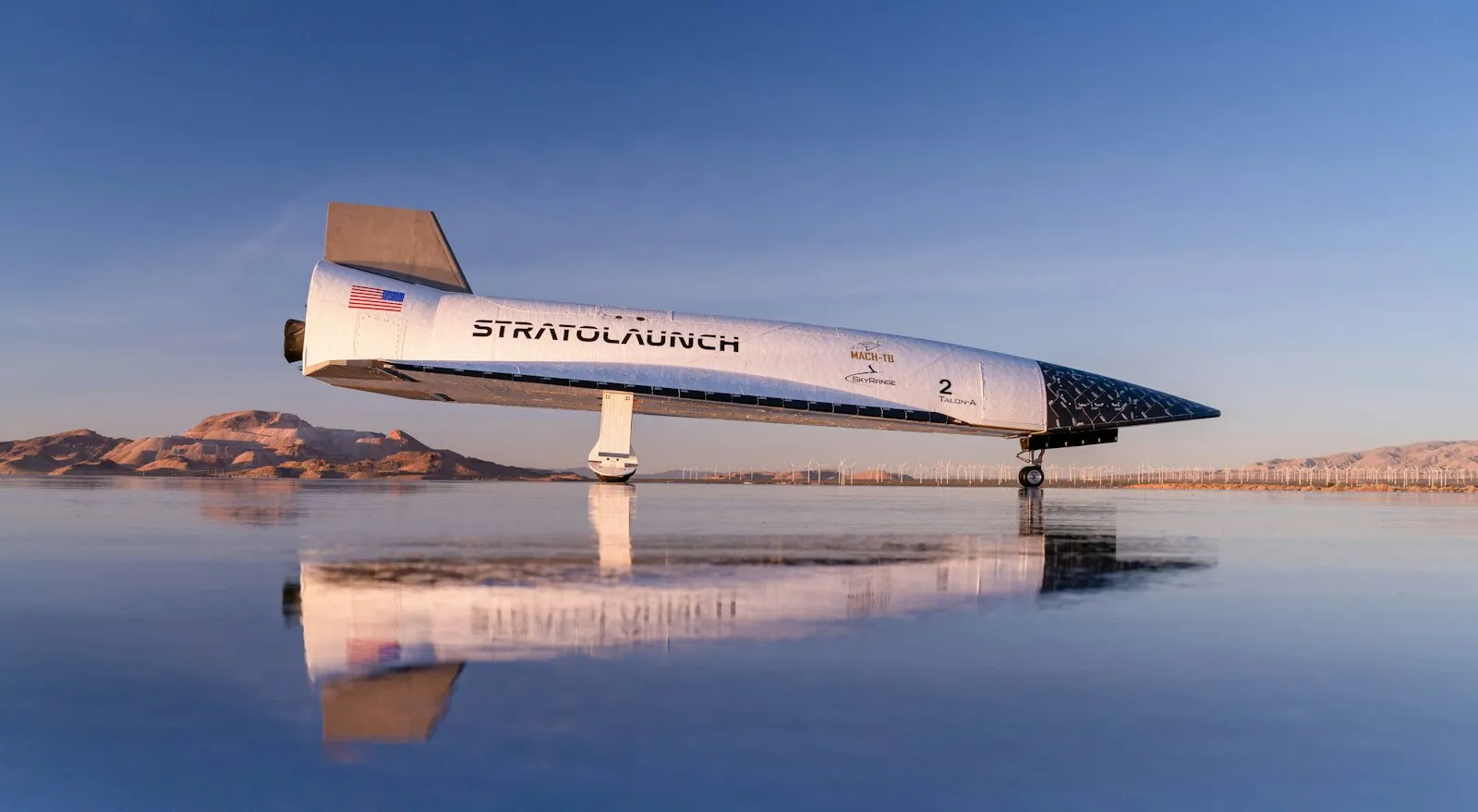 Talon-A parked on a dry lakebed, reflected in standing water